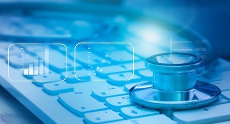 A stethoscope resting on a keyboard beside simple chart graphics, in blue tones