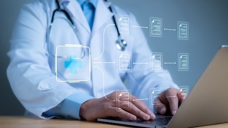 A physician working at a laptop with connected data overlays
