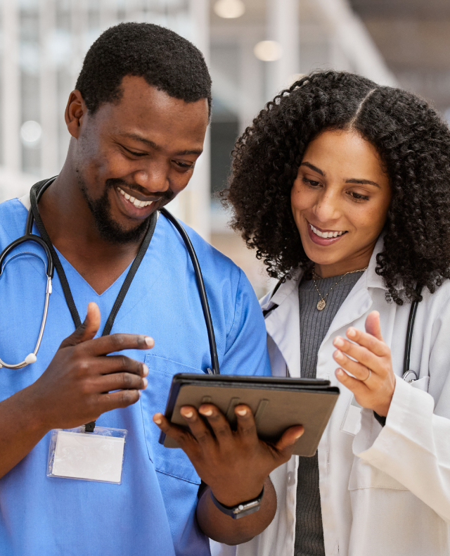 Two clinicians smile while reviewing a tablet together