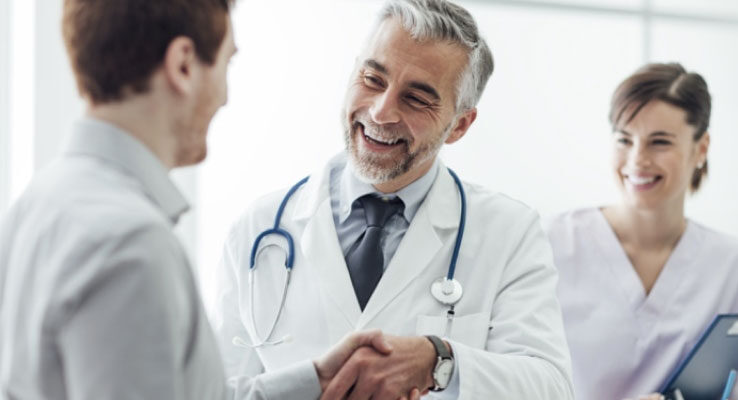 Doctor shacking a patients hand with a nurse in the background