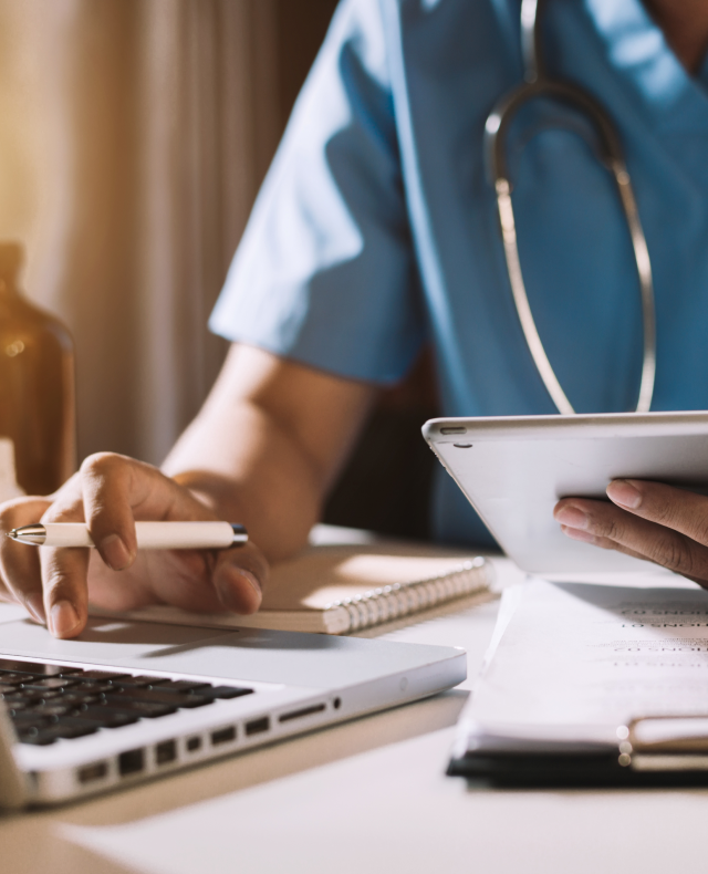 nurse with iPad, laptop, notepad and pen