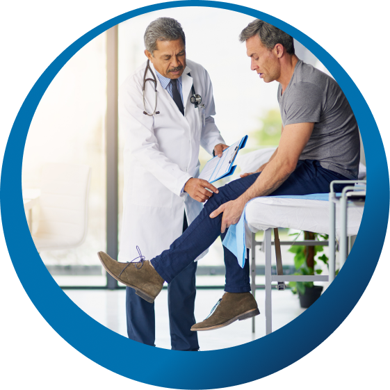 An orthopedic physician examining a patient's knee in an exam room.
